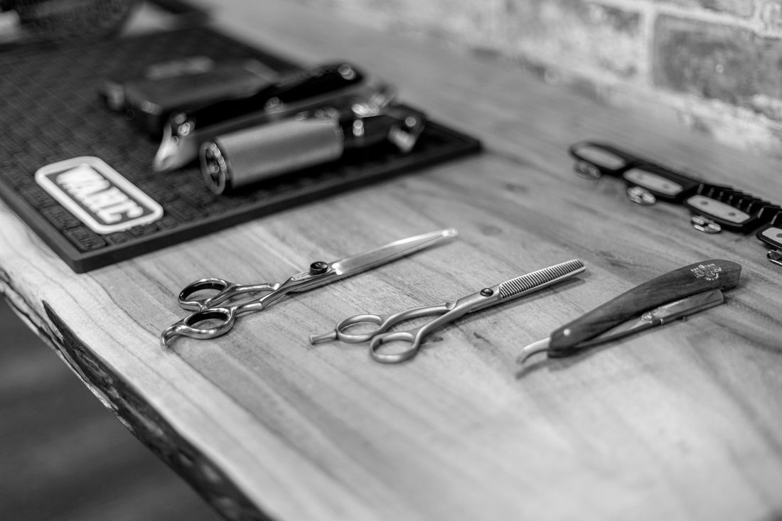 Barber scissors and clippers laid out on a wooden table