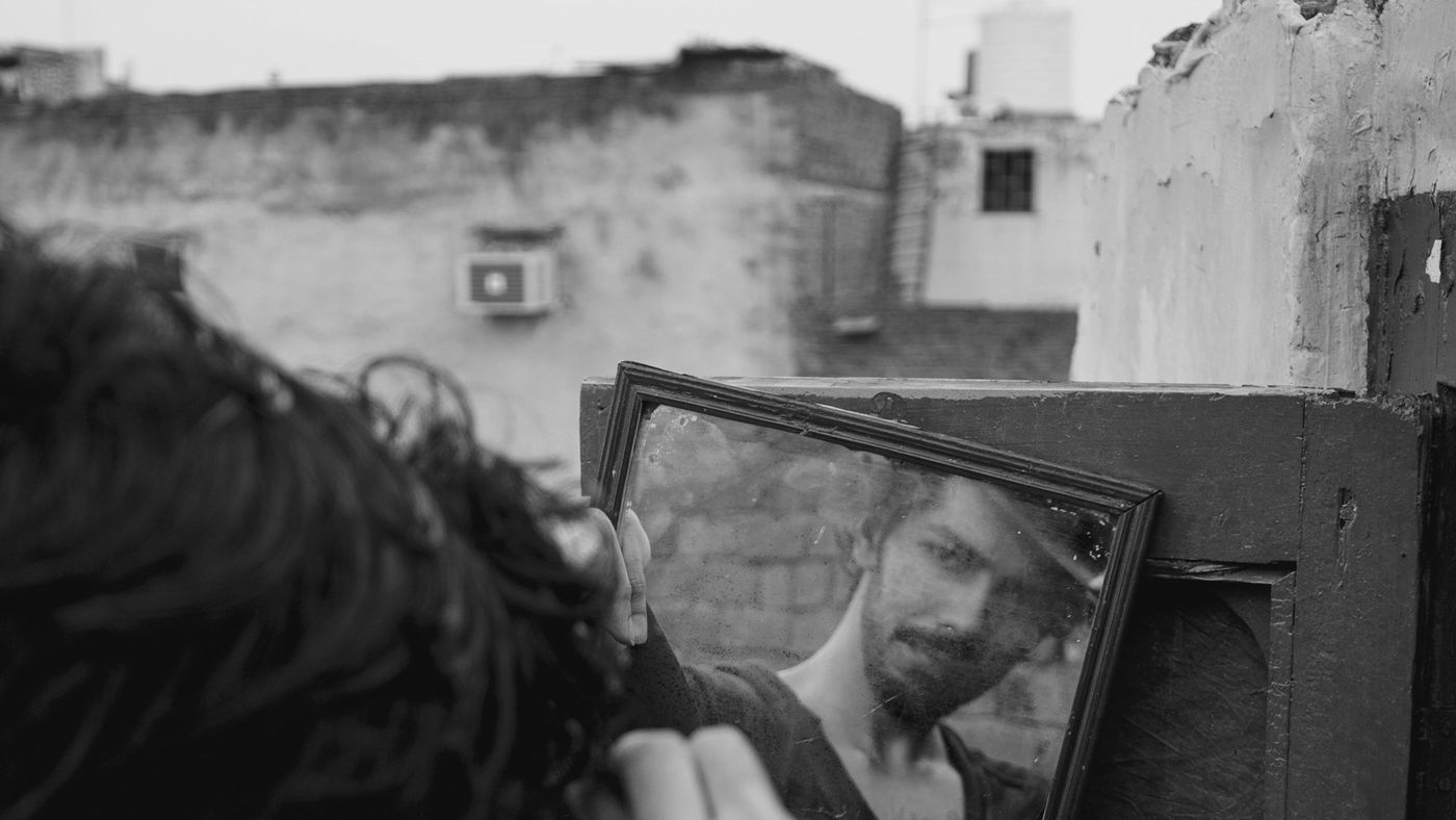 A man checking his haircut in a mirror propped outdoors