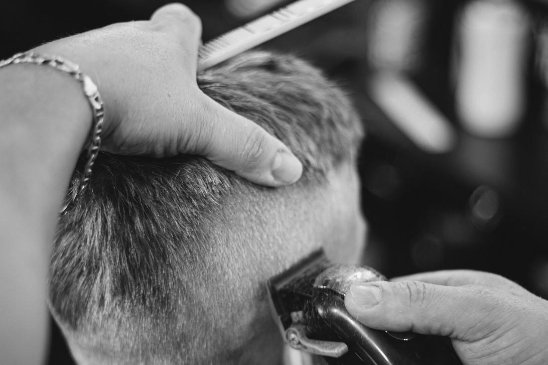 A barber running clippers up the side of a client's head