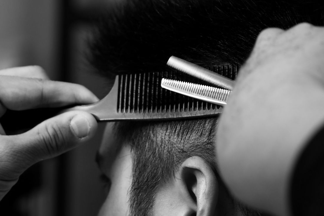 A barber blending hair with thinning shears and a comb