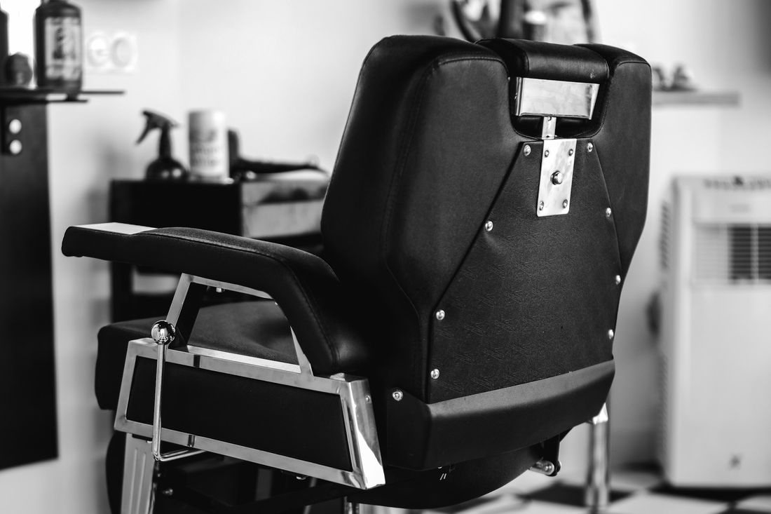 A black leather barber chair in a clean, bright white room