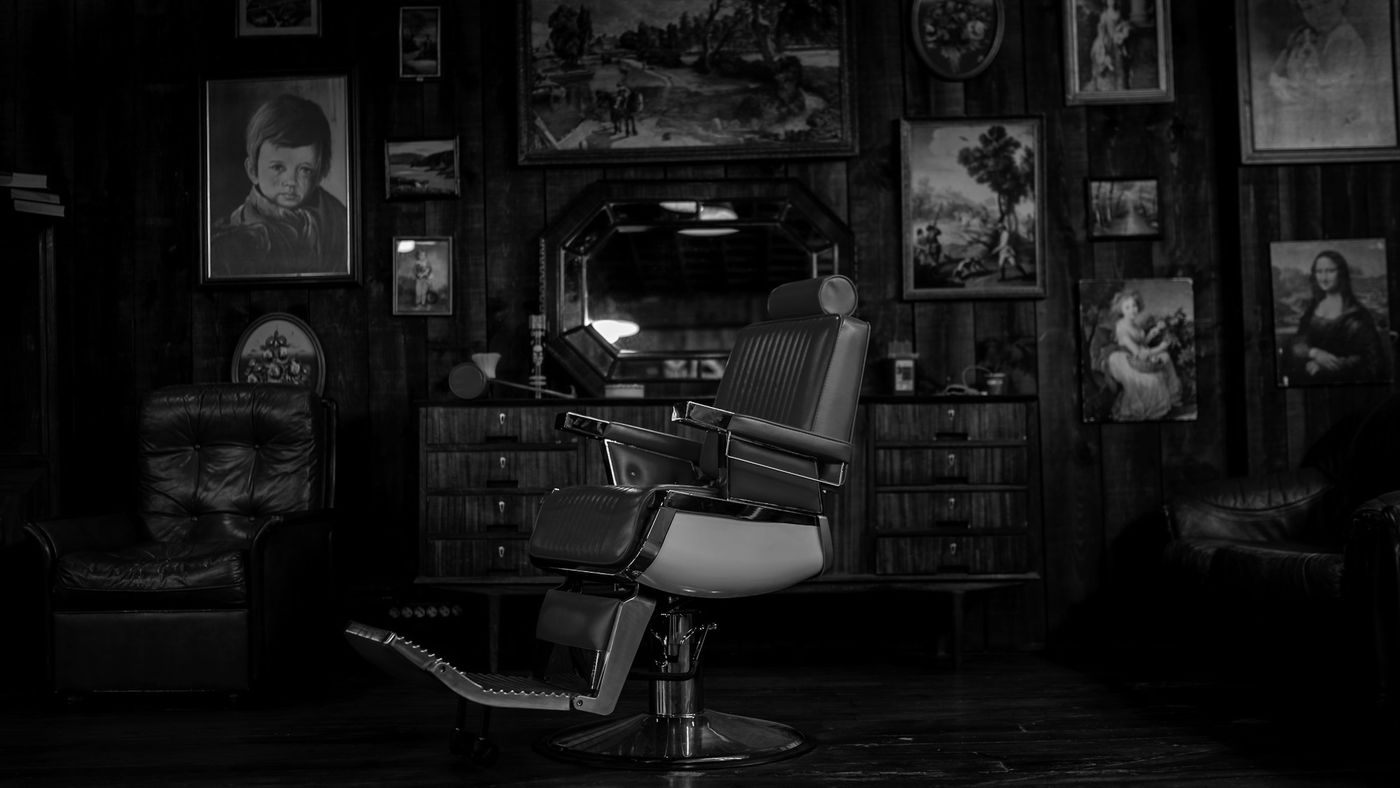 A vintage leather barber chair in a shop lined with framed pictures