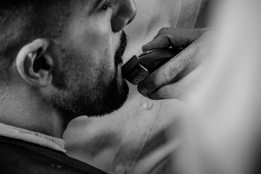 A clipper trimming a man's beard and mustache, close up