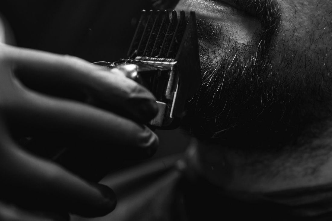 A trimmer working along the edge of a man's beard