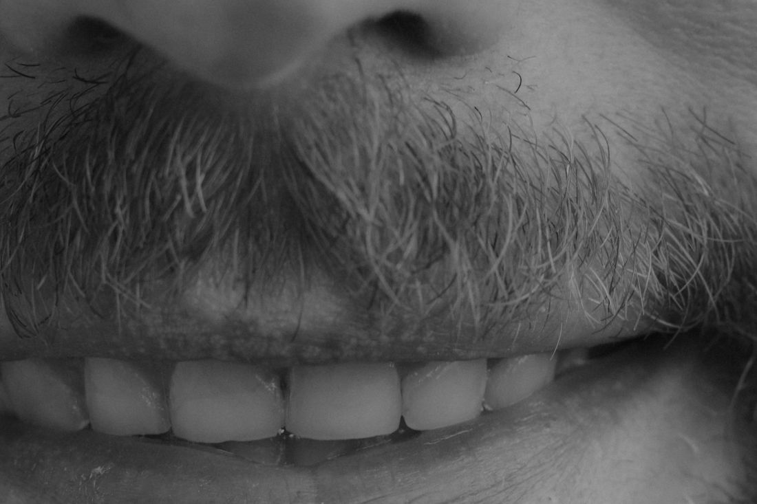 Close-up of a smiling mouth surrounded by a thick beard