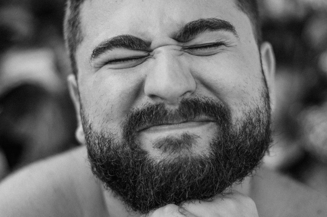 A bearded man squinting with a pained expression