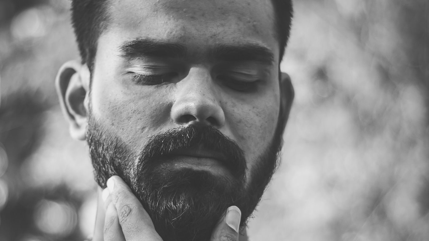 A man rubbing his short beard with one hand