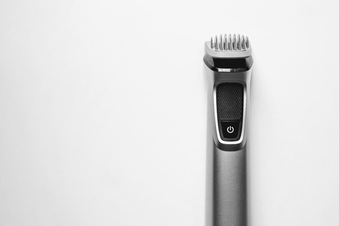 A beard trimmer standing upright on a white surface