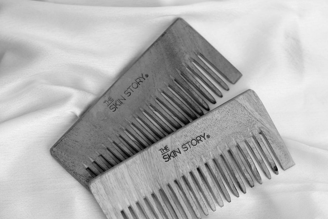 Two wooden beard combs resting on a white sheet
