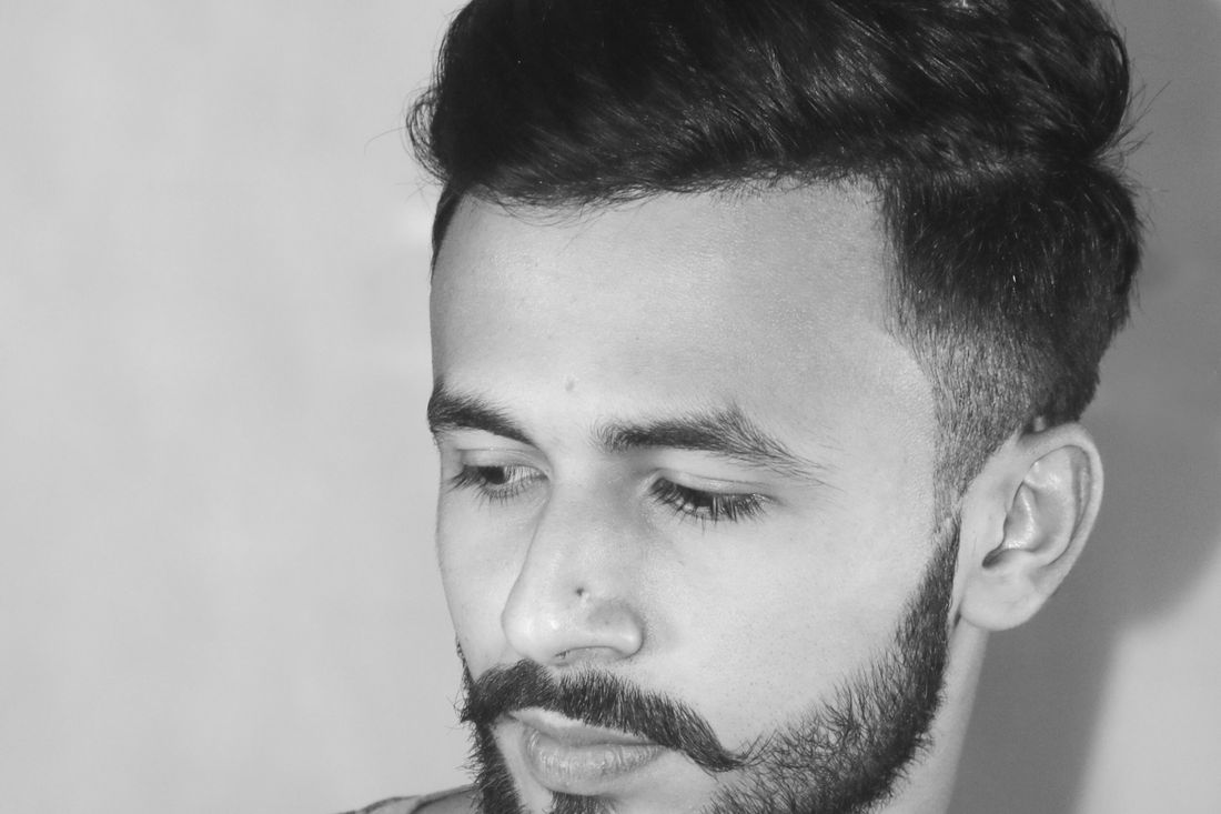 A man with styled hair and a short, even beard