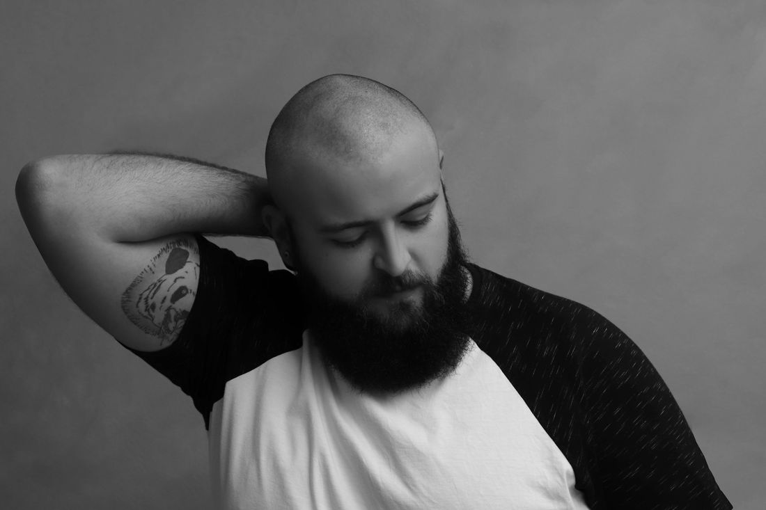A bald man with a full beard resting a hand behind his head
