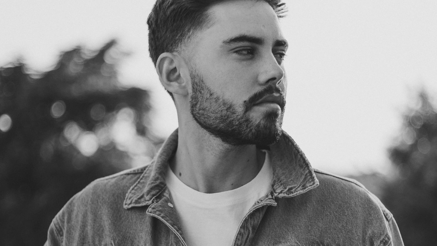 A man with a short, full beard wearing a denim jacket