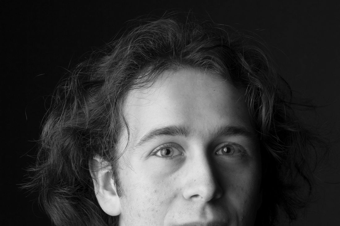 A young man with longer, wavy hair falling forward
