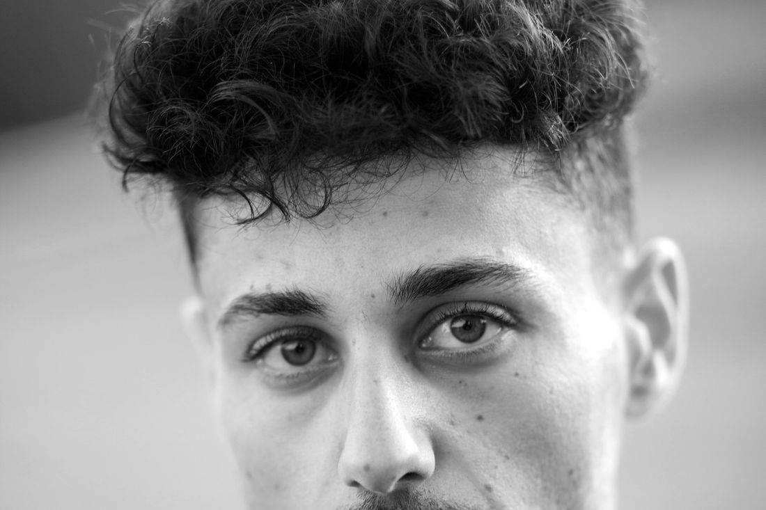 A young man with a curly top and short sides