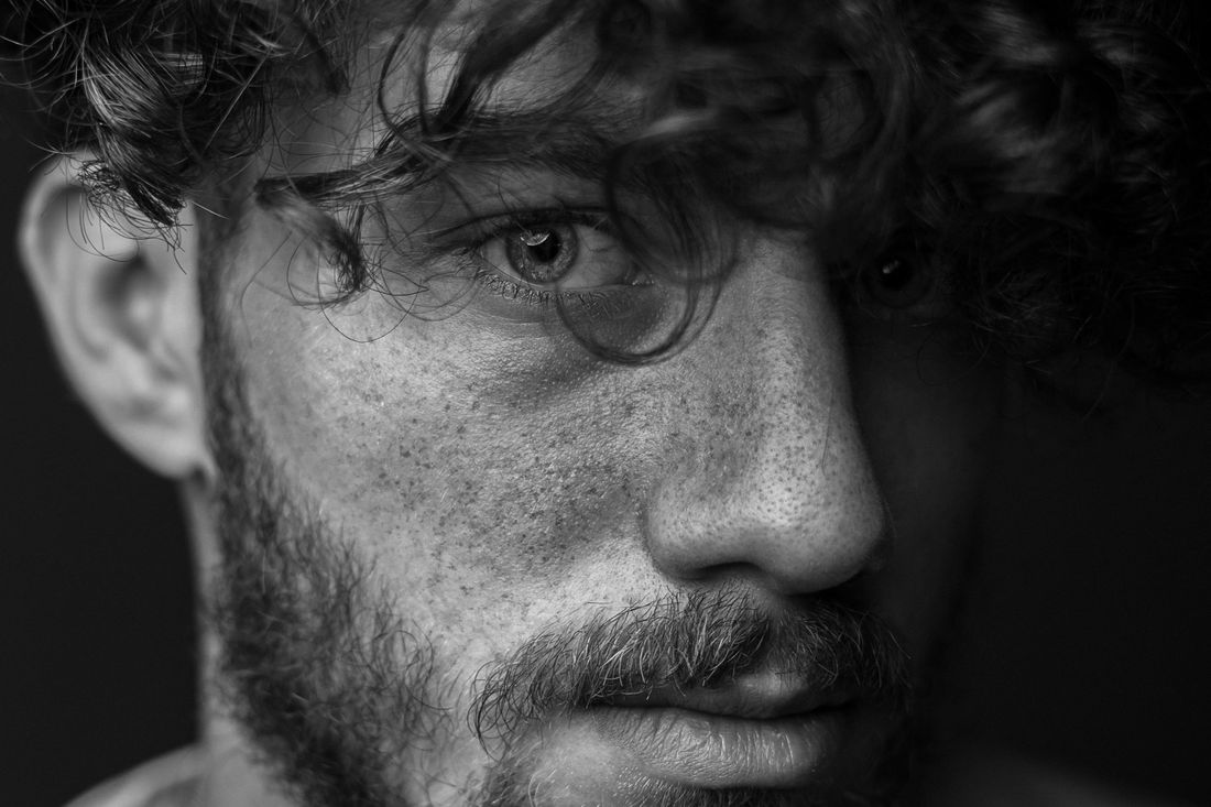 A man with curly hair, glasses and a beard