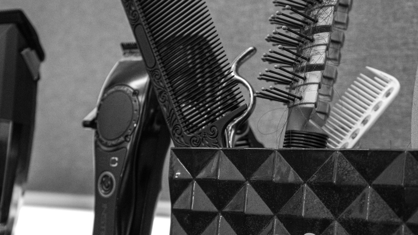 Hair clippers and combs standing in a holder at a barber's station