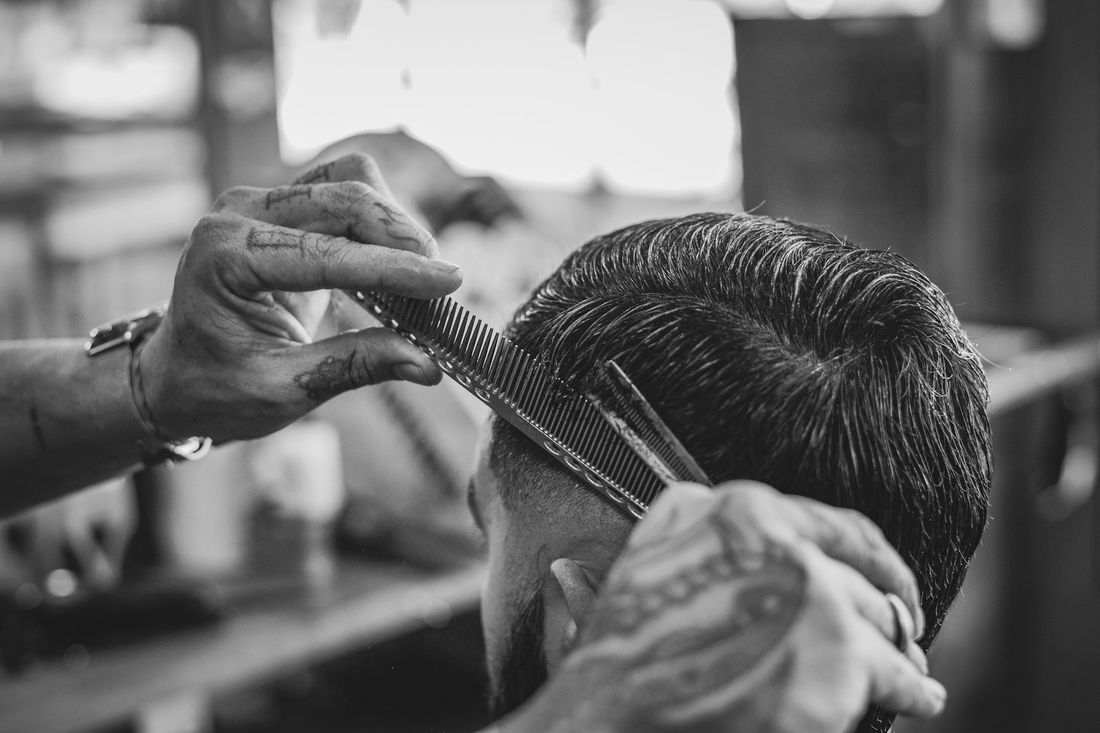 A barber combing and cutting the top of a client's hair
