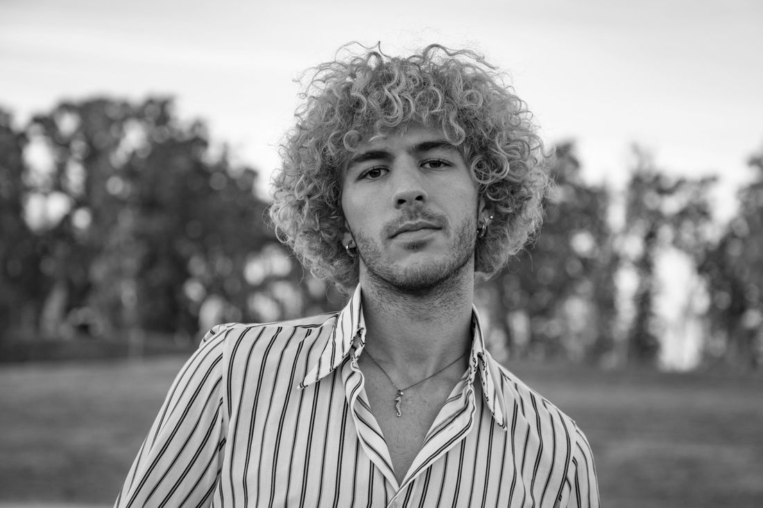 A young man with a full head of light curly hair, outdoors