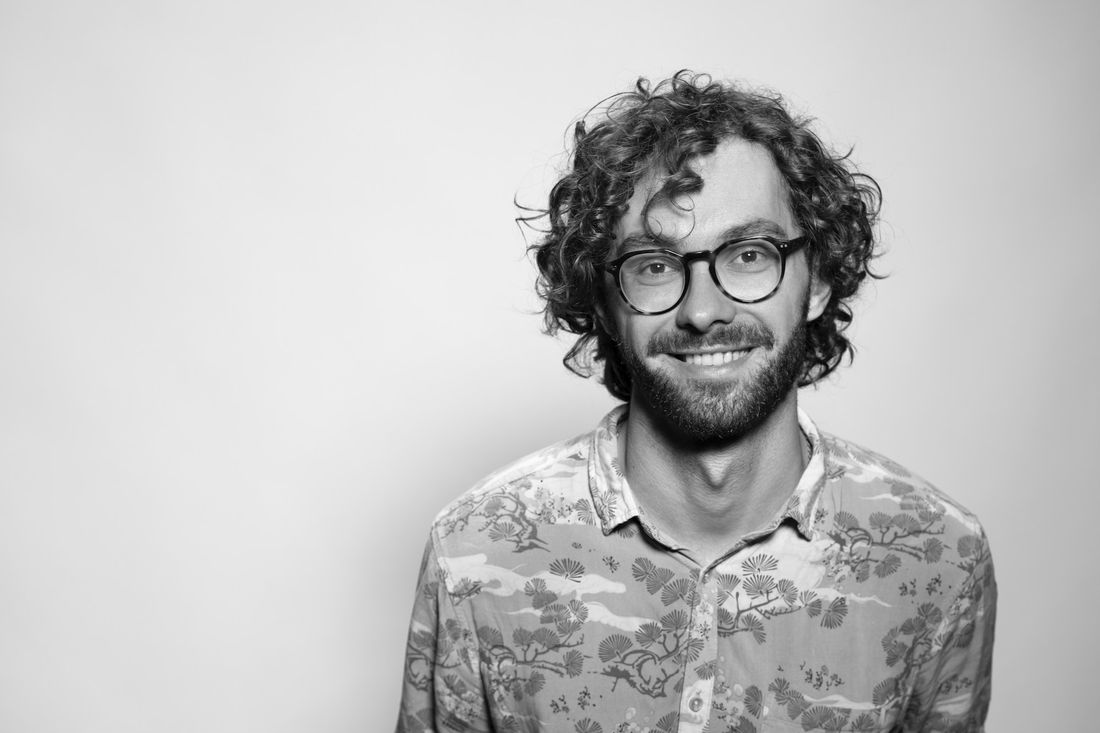 A smiling man with glasses and short curly hair