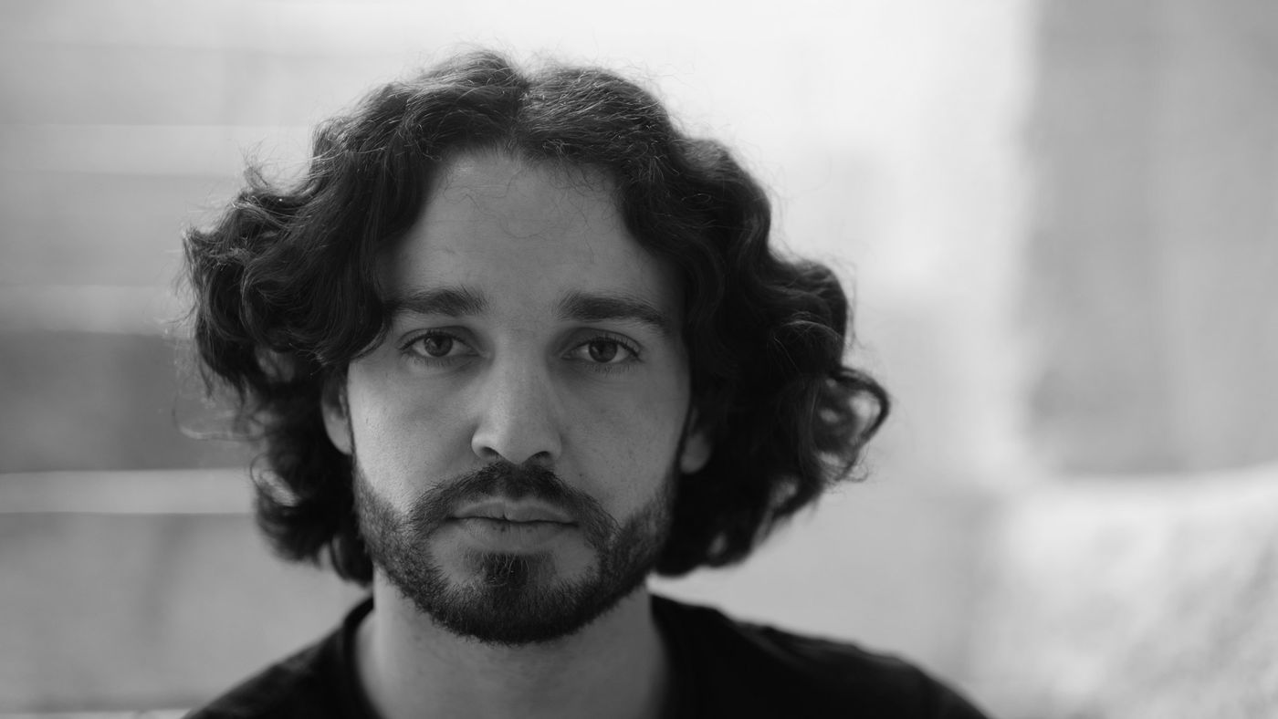 A man with shoulder-length curly hair and a short beard