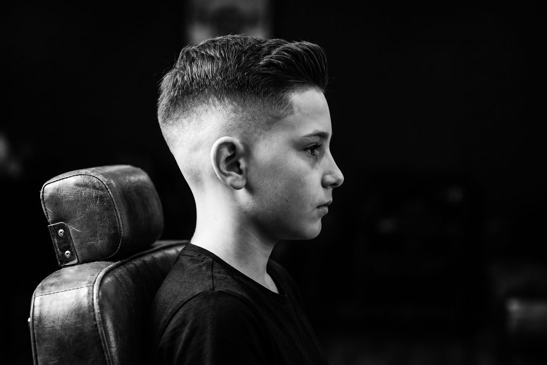 A boy with a high fade haircut, very short sides blended from near the widest point of the head into length on top
