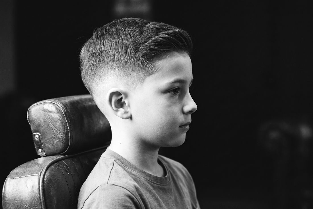 A boy with a low fade haircut, the blend starting just above the ear with most of the side keeping its length