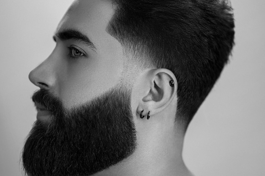 Side profile of a man with a full, dense beard and a sharp fade