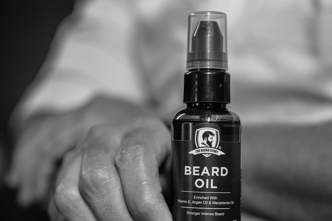 A hand holding a small bottle of beard oil