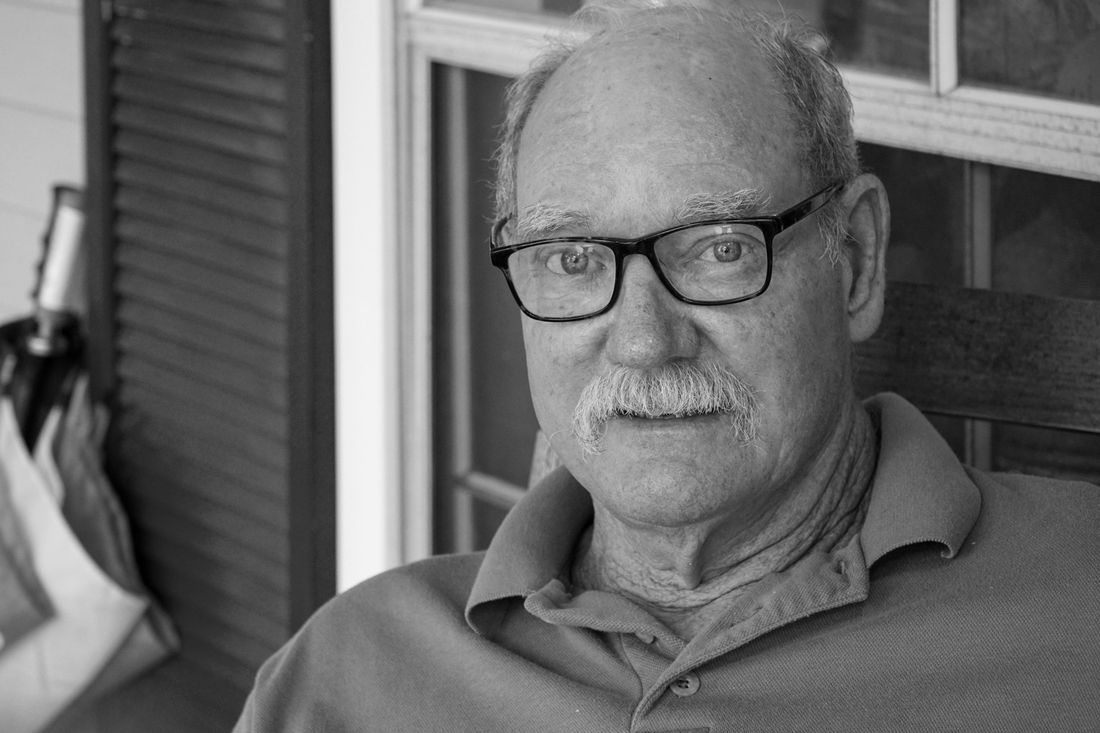 An older man with glasses and a neat gray mustache