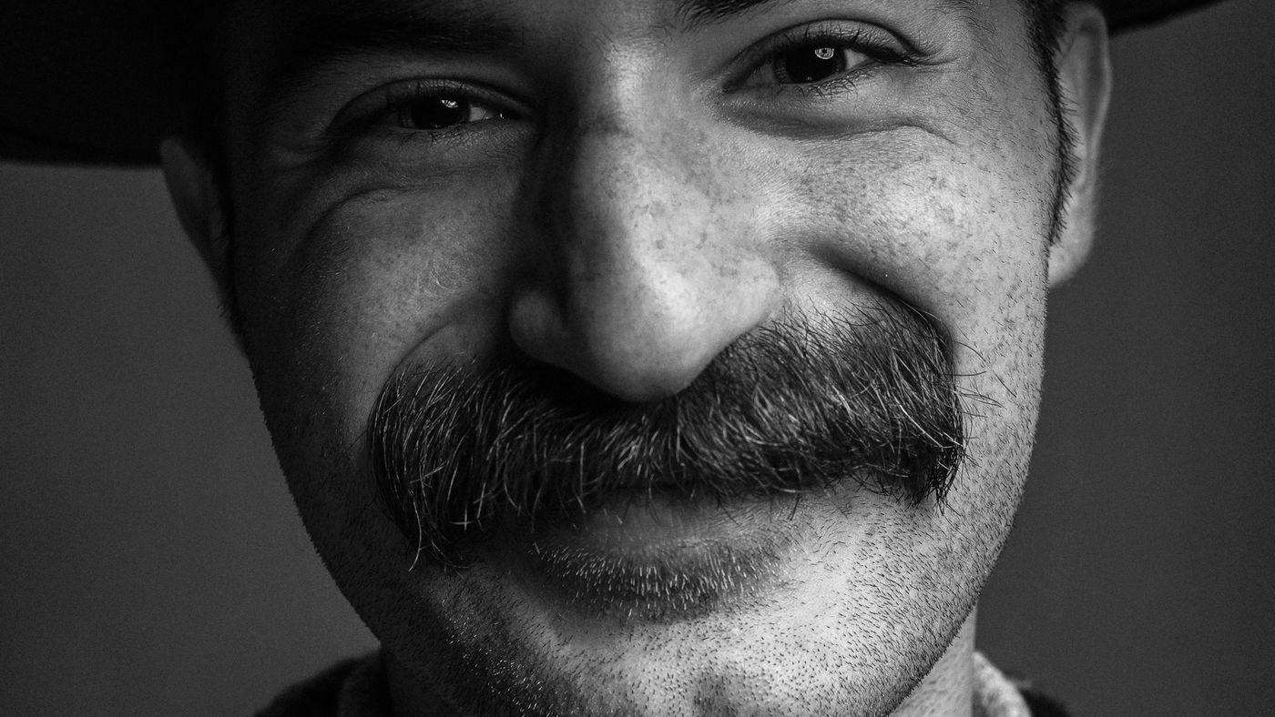 A smiling man with a thick mustache, close up
