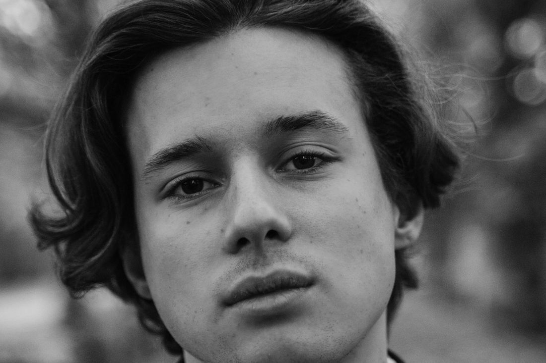 A young man with chin-length hair looking at the camera