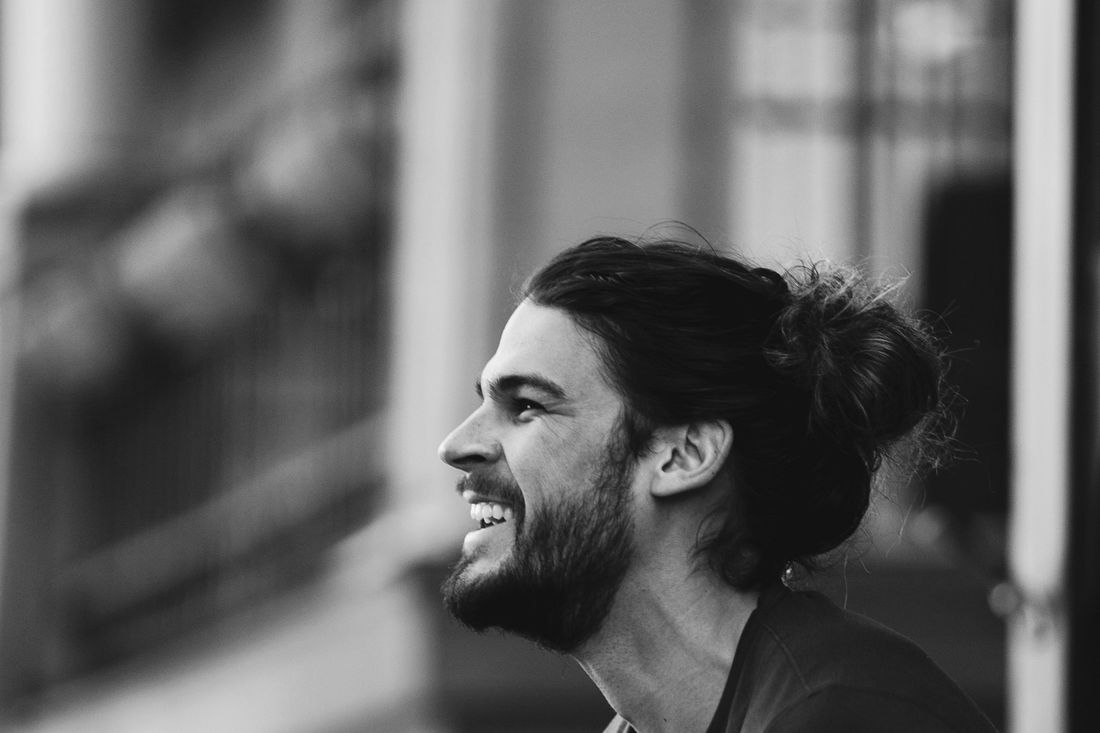 A smiling man with his hair tied back in a bun