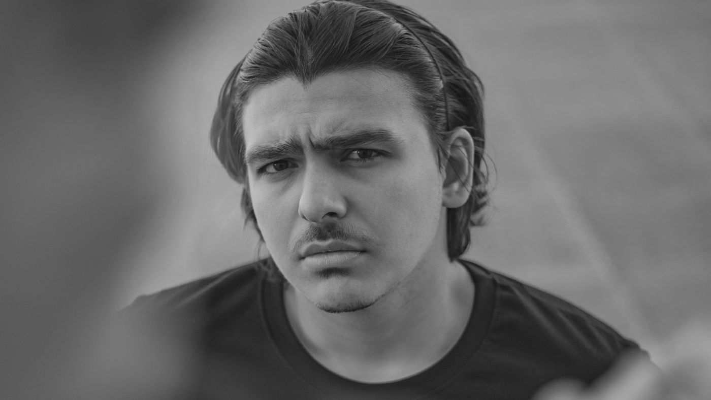 A young man with medium-length hair pushed back