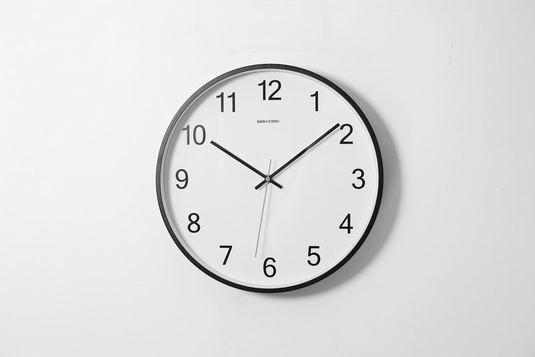 A round wall clock on a white wall