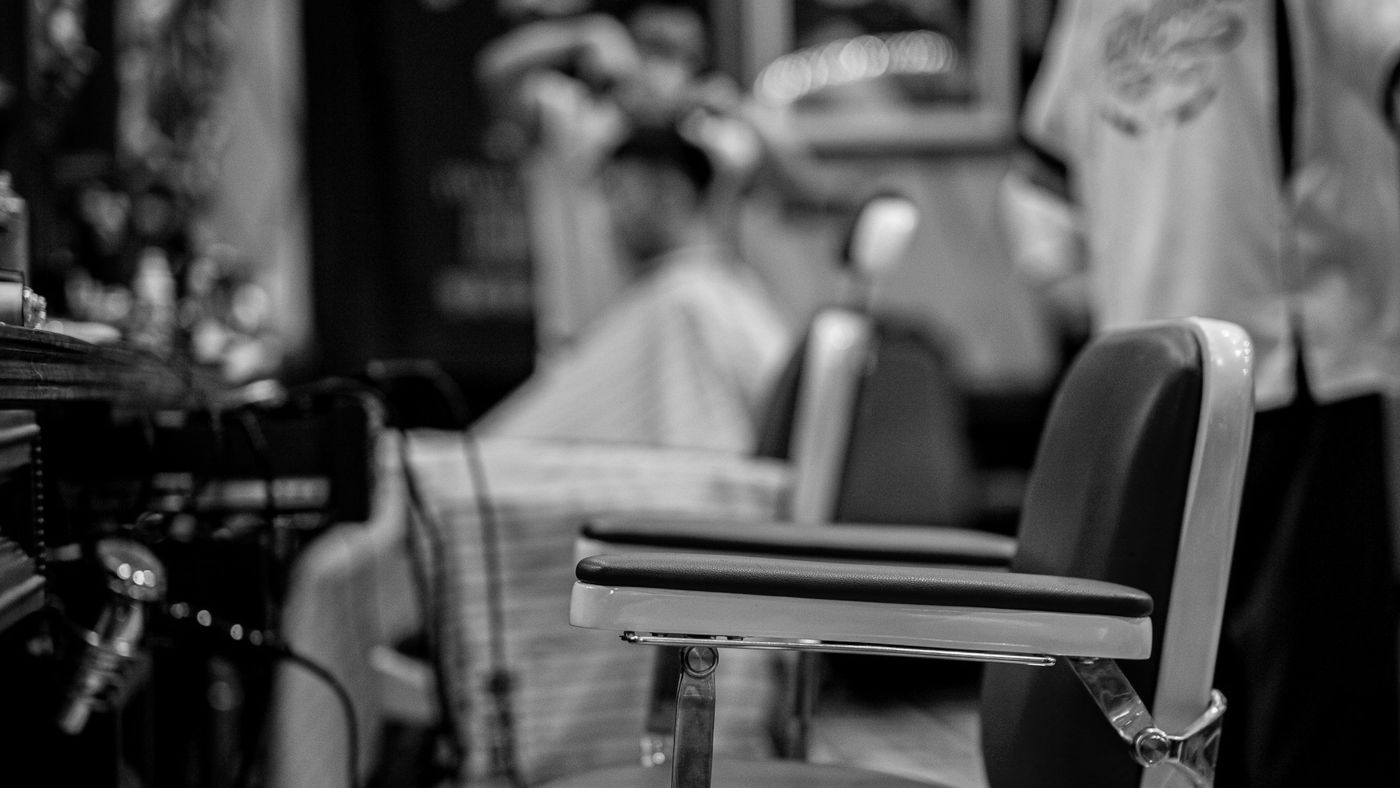 A leather barber chair in soft focus inside a barbershop