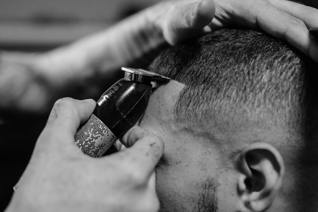 Close-up of clippers fading the side of a man's head