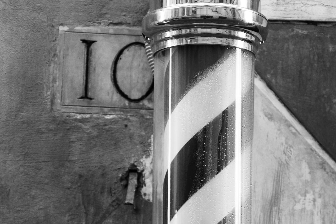 A traditional striped barber pole against a stone wall