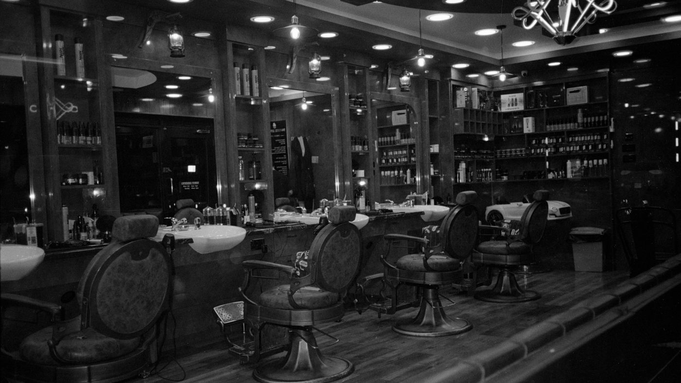 A dark, empty barbershop with a row of barber chairs and mirrors
