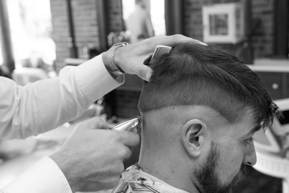 A barber blending the side of a bearded client's haircut