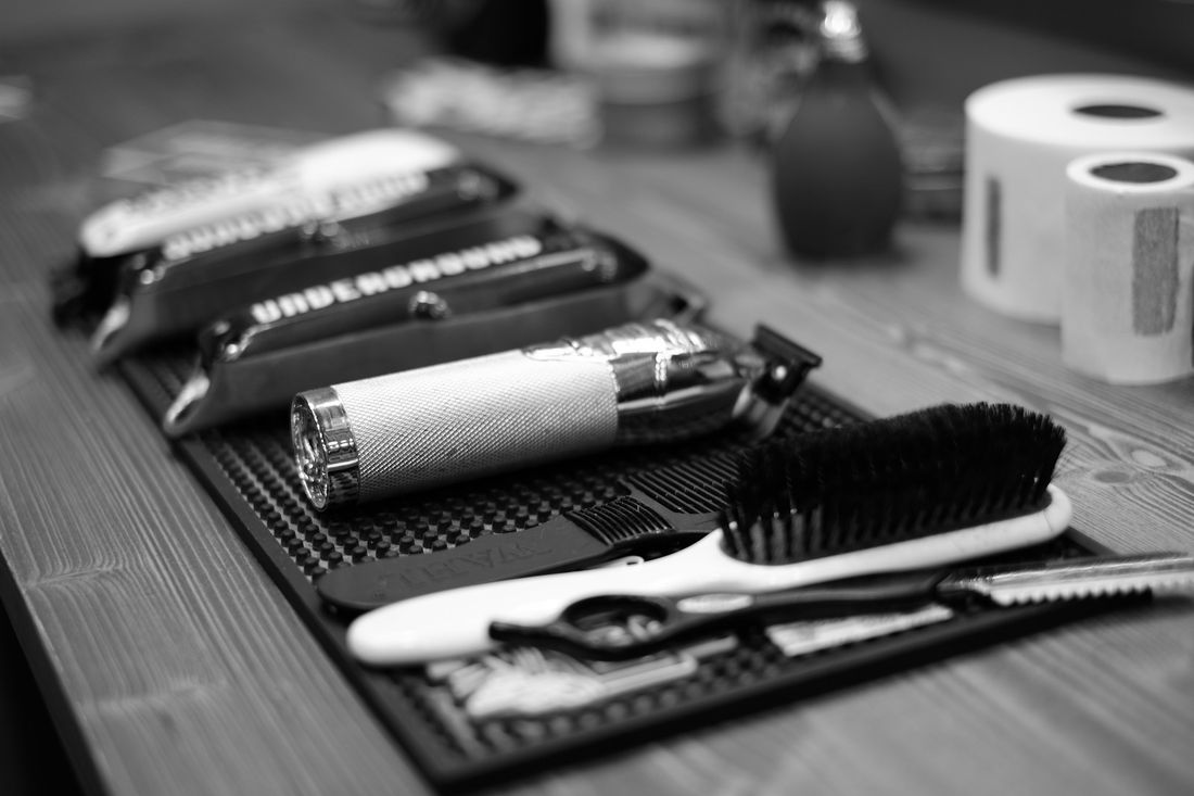 Clippers, a brush and grooming tools lined up on a barbershop counter