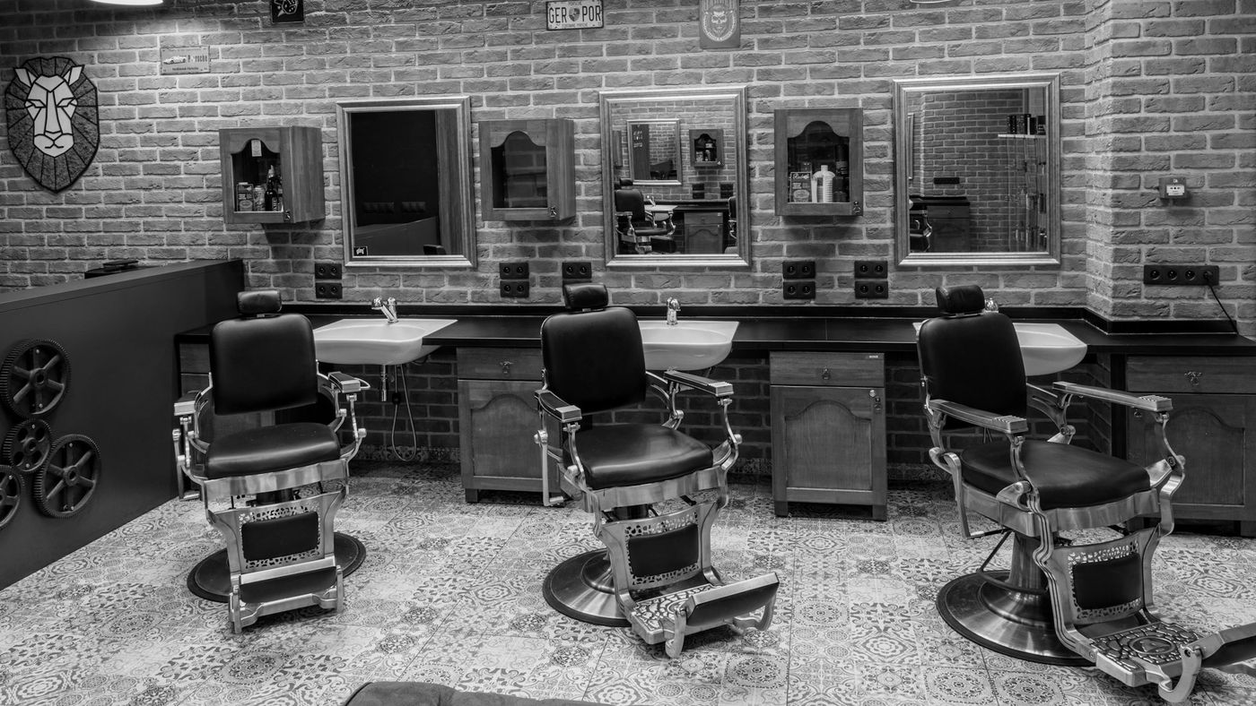 A long brick-walled barbershop with a row of vintage barber chairs