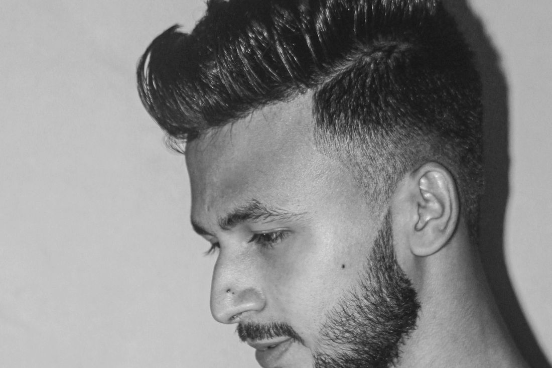 A man in profile with short tapered sides and a slightly longer textured top