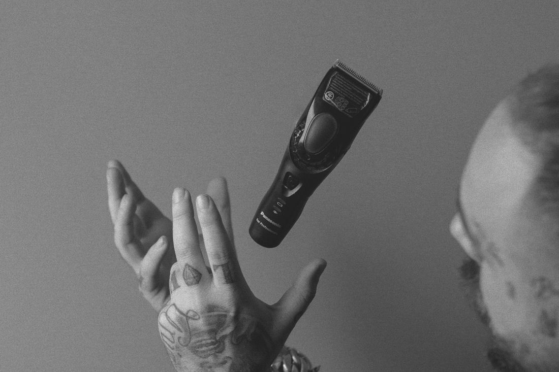 A tattooed hand holding a hair clipper