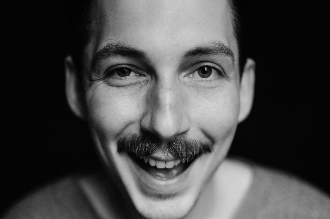 A smiling man with a neat mustache