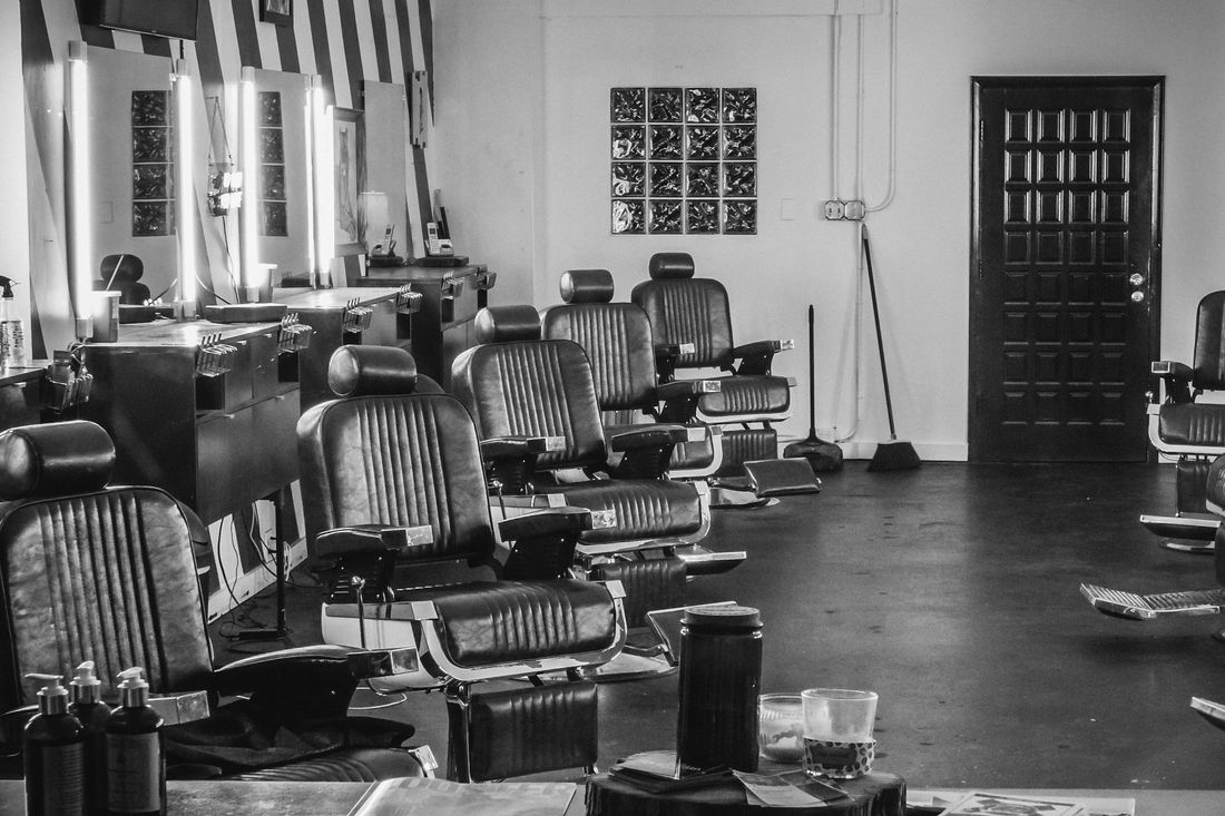 A long row of empty brown leather barber chairs in an old-fashioned shop