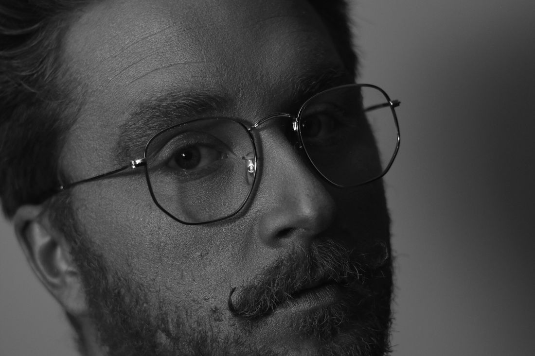 A man with glasses and hair swept up at the front