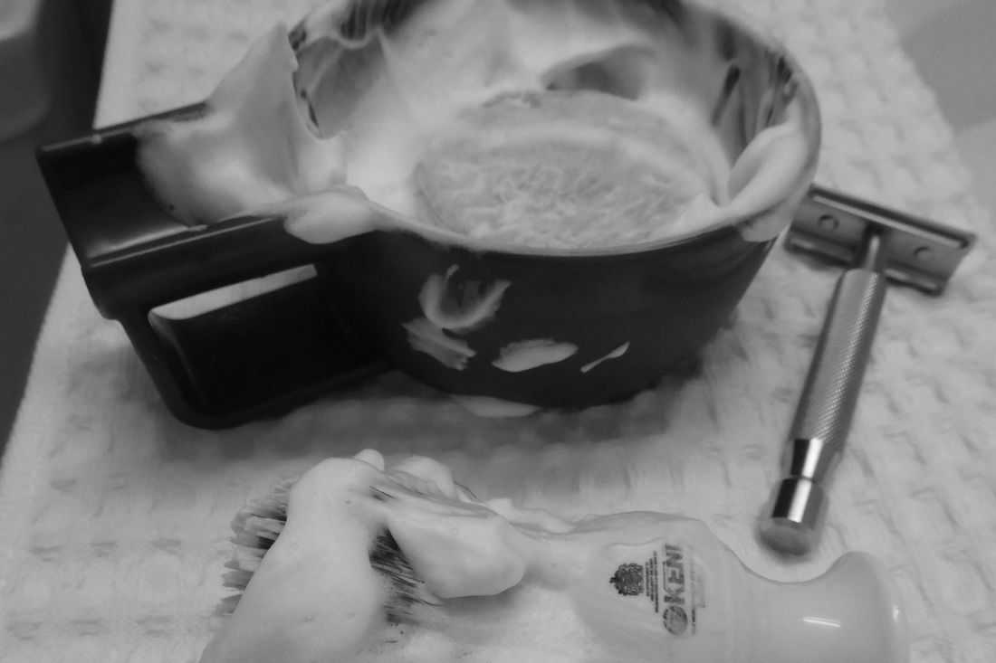 A bowl of shaving lather beside a safety razor