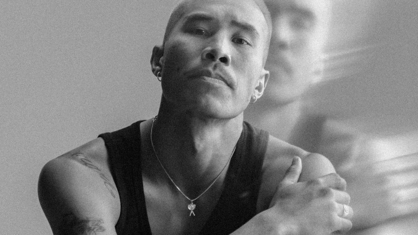 A man with a short buzz cut in profile, with a blurred reflection behind him