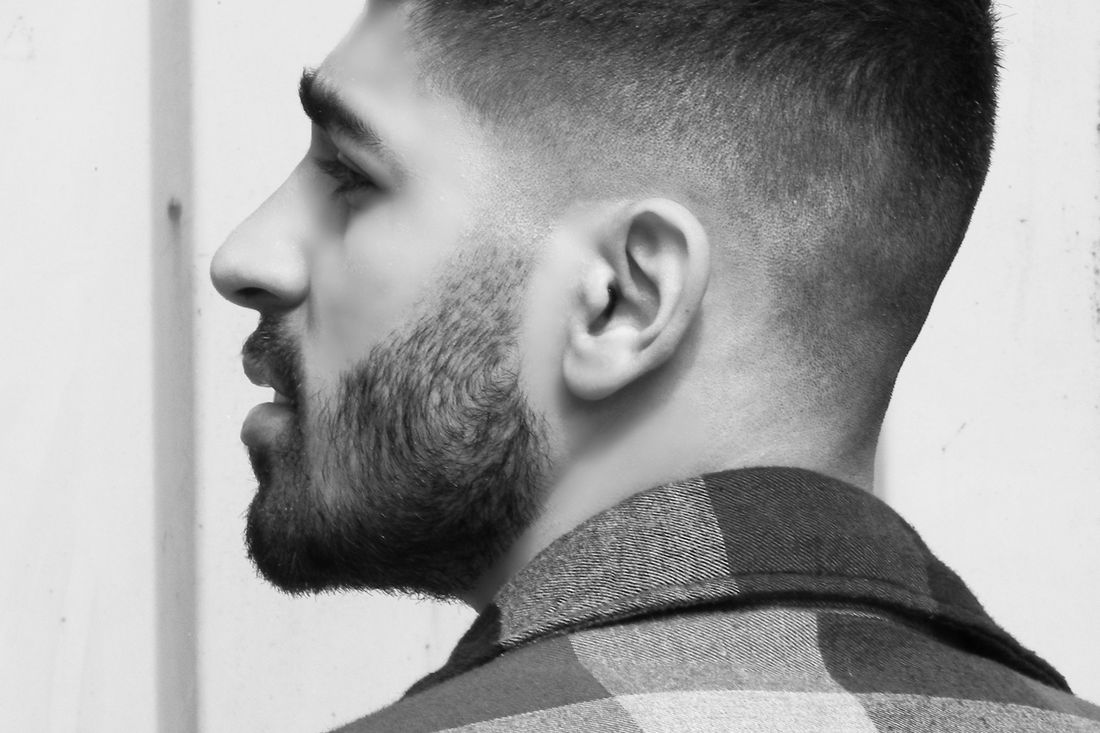 Profile of a man with a short fade, textured top and a shaped beard