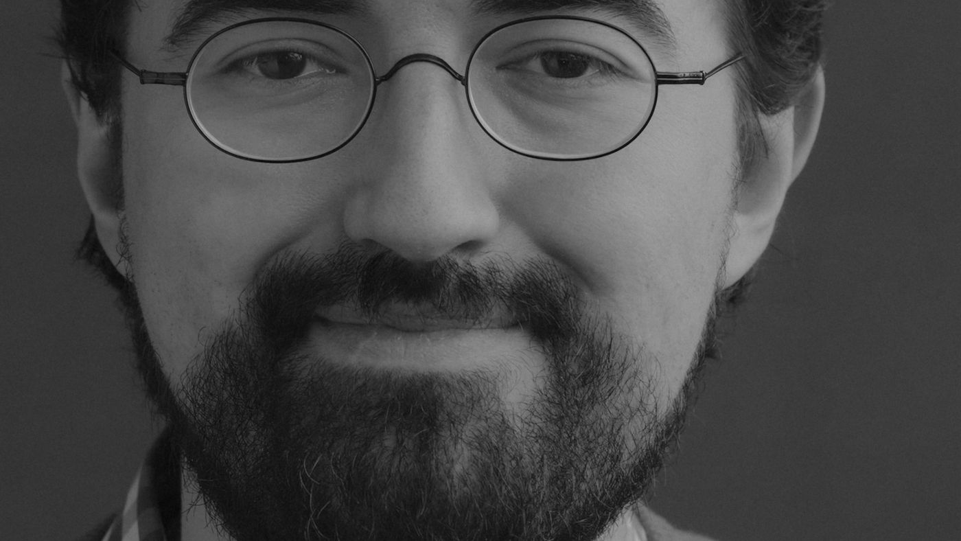A smiling man with round glasses and a short beard